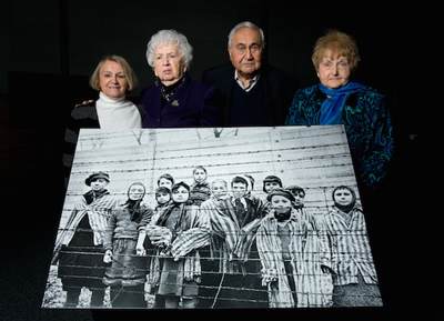 Survivors pose with an enlargement of the iconic photograph taken of them on Jan. 27, 1945. From left are Paula Lebovics, Miriam Ziegler, Gabor Hirsch and Eva Kor. (Photo courtesy of Ian Gavan/Getty Images)