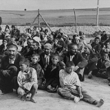A group of Gypsy prisoners, awaiting instructions from their German captors, sit in an open area near the fence in the Belzec concentration camp.

Belzec, 1940 © USHMM, courtesy of Archiwum Dokumentacji Mechanicznej.