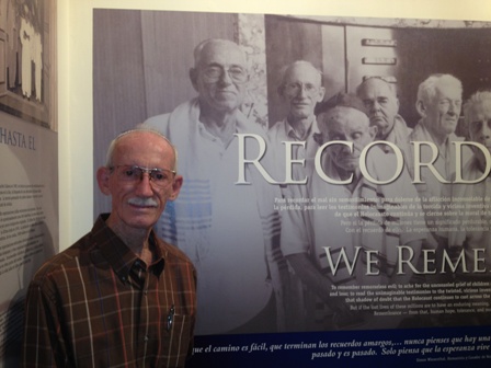Simon Goldstein, whose story is part of the Exhibit, stands in front of a wall that bears his image (second from left).