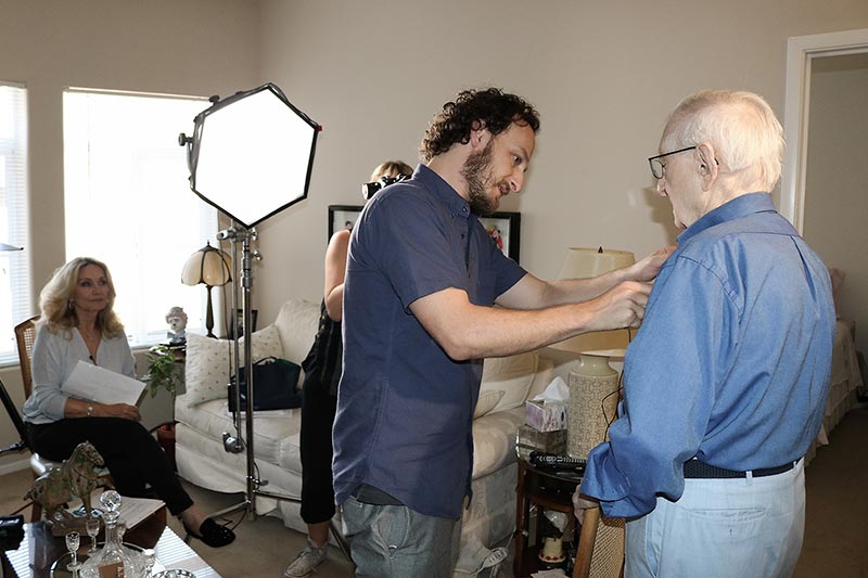 Videographer Jeff Schneider puts a mic on Holocaust Survivor John Adler who gave his testimony in 2018 at the age of 94 as part of the Last Chance Testimony Collection.