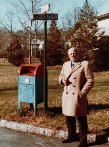 Oskar Schindler stands next to a street sign bearing his name.