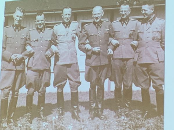 Hiding the harsh realities around them, a group of concentration camp guards happily pose for the camera.