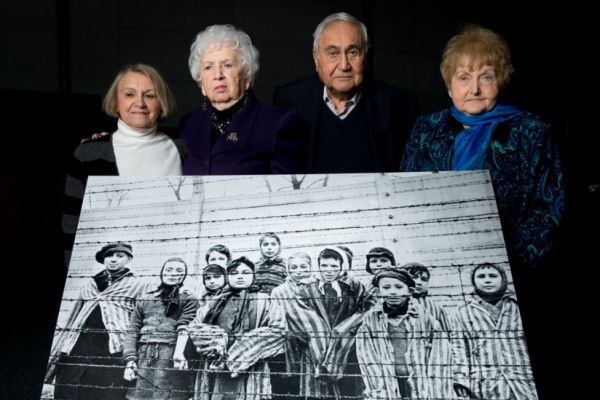 Survivors pose with an enlargement of the iconic photograph taken of them on Jan. 27, 1945. From left are Paula Lebovics, Miriam Ziegler, Gabor Hirsch and Eva Kor. (Photo courtesy of Ian Gavan/Getty Images)